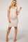 woman wearing a beige short sleeve maternity dress and showing her baby bump
