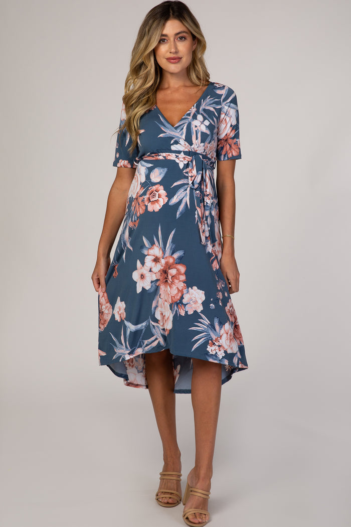 woman wearing a blue floral maternity wrap dress with short sleeves and a high-low hemline