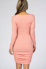 woman wearing a light pink long sleeve bodycon dress with ruching detail at the back