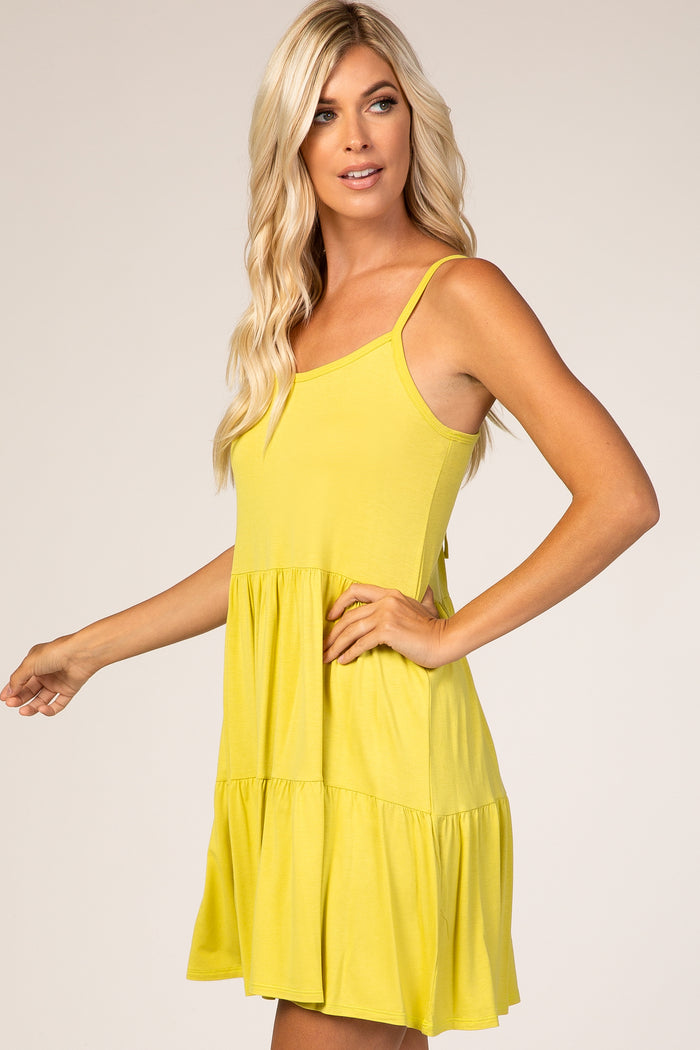 woman wearing a bright yellow spaghetti strap tiered mini dress with a flattering fit