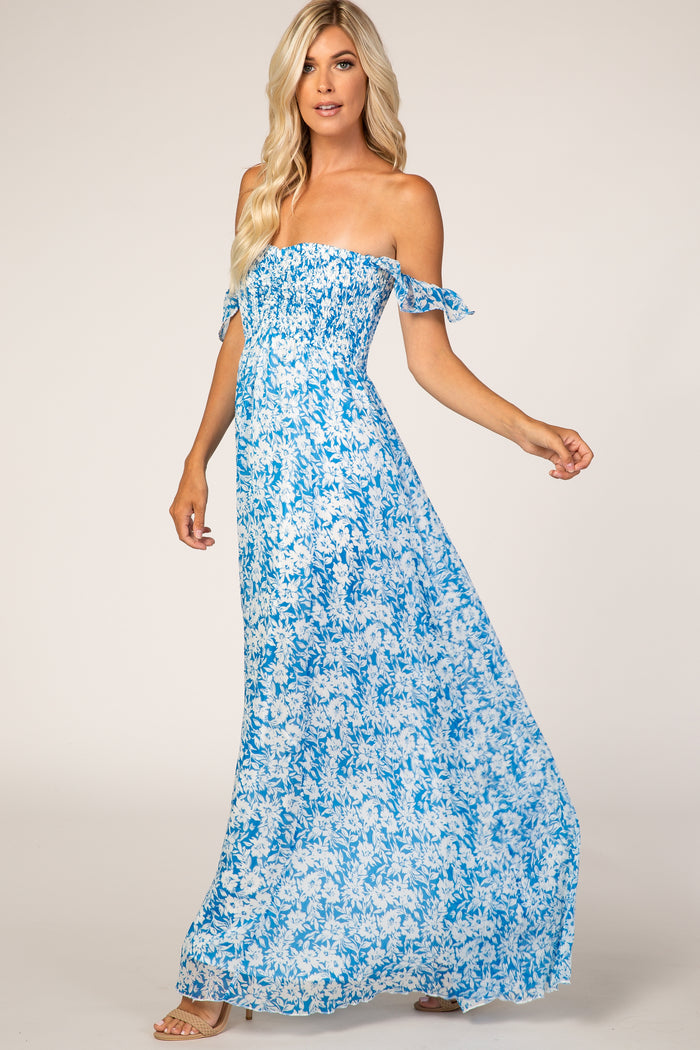 woman wearing a blue and white floral off-the-shoulder maxi dress with a smocked bodice and flowing skirt