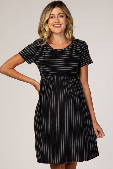 woman wearing a black and white striped maternity dress with a fitted top and flowy skirt, highlighting her baby bump