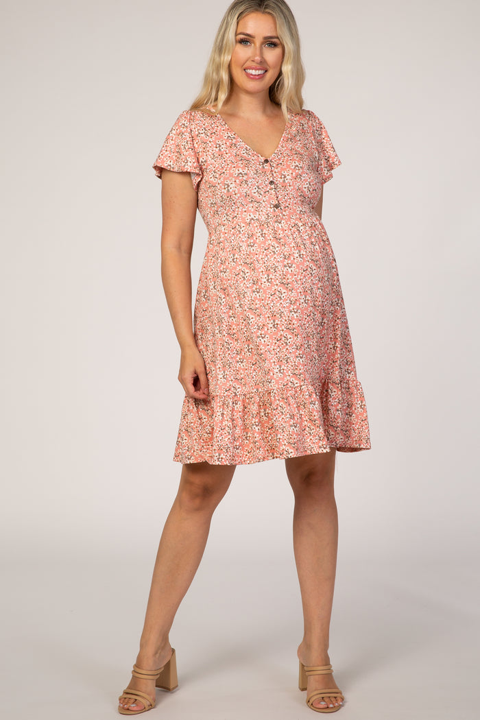 woman wearing a pink floral maternity dress with short sleeves and a ruffled hem, showing off her baby bump