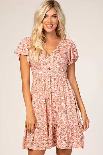 woman wearing a pink floral short sleeve dress with a v-neck and ruffled hem