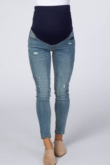 woman wearing a pair of distressed maternity skinny jeans with a navy blue over-the-bump waistband