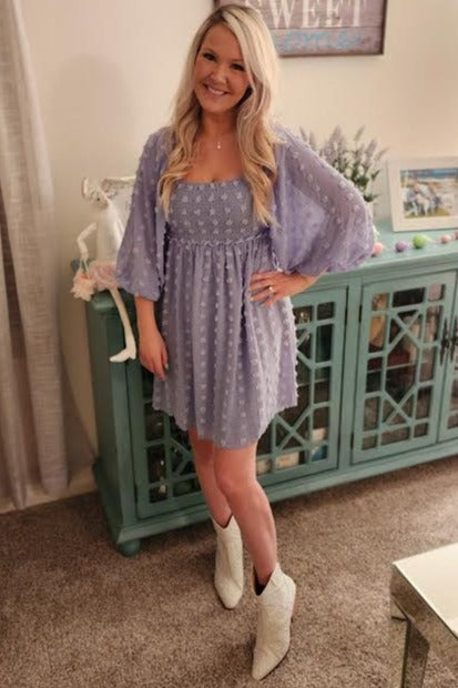 woman wearing a lavender short puff sleeve dress with smocking details and white cowboy boots