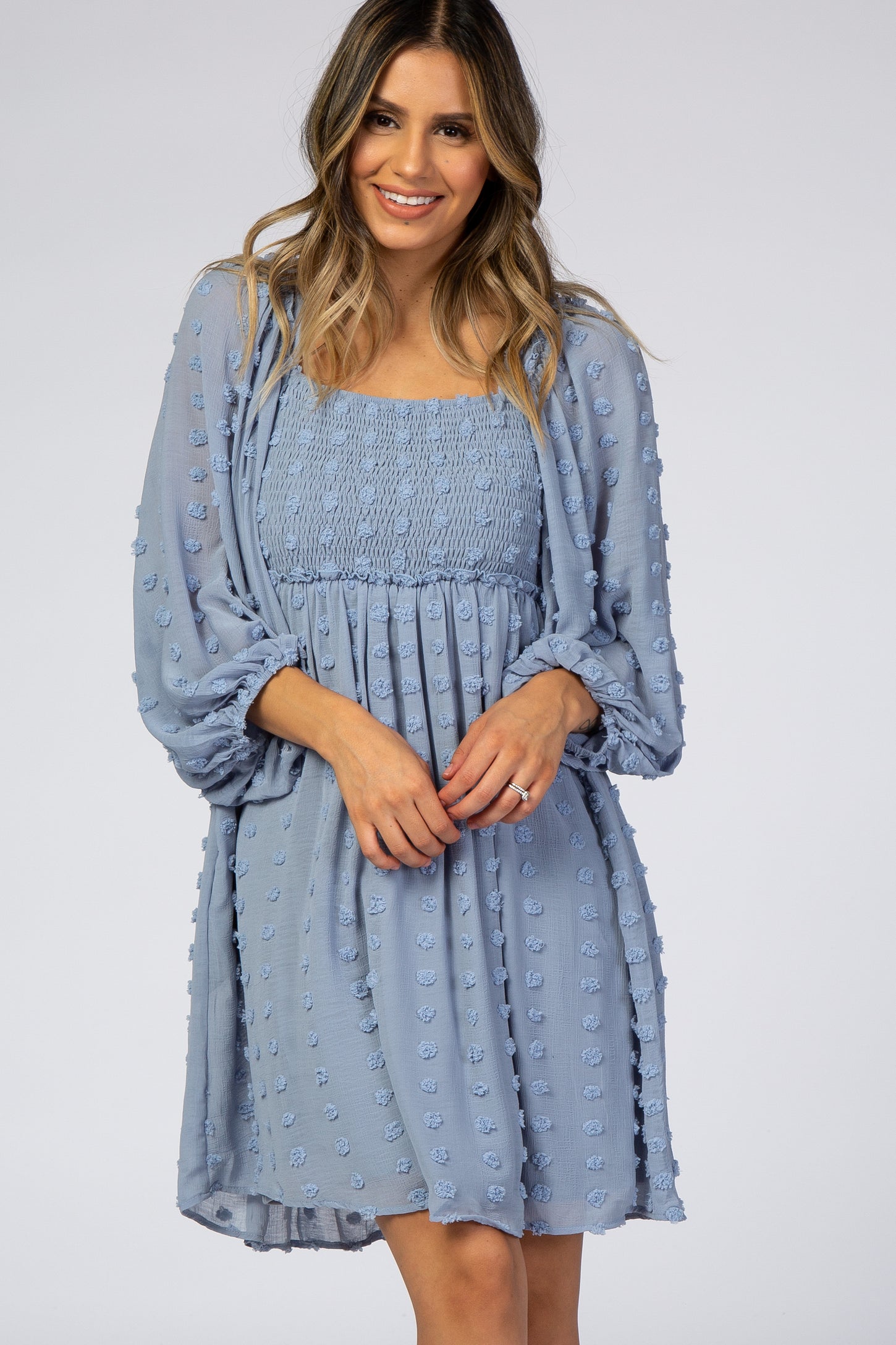woman wearing a light blue short dress with a smocked bodice and puff sleeves, featuring 3D floral embellishments