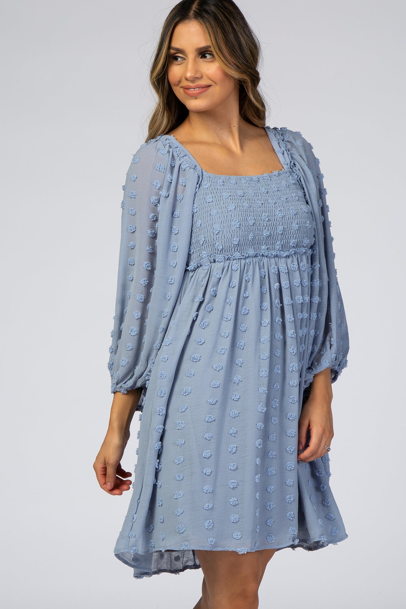 woman wearing a light blue puff sleeve dress with a smocked bodice and textured dot details