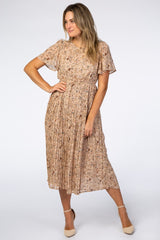 woman wearing a beige floral pleated midi dress with flutter sleeves and tan heels
