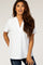 woman wearing a white short sleeve blouse with a v-neck and textured fabric, smiling at the camera