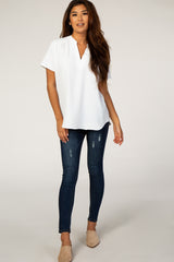 woman wearing a white short sleeve blouse with a v-neckline and blue skinny jeans