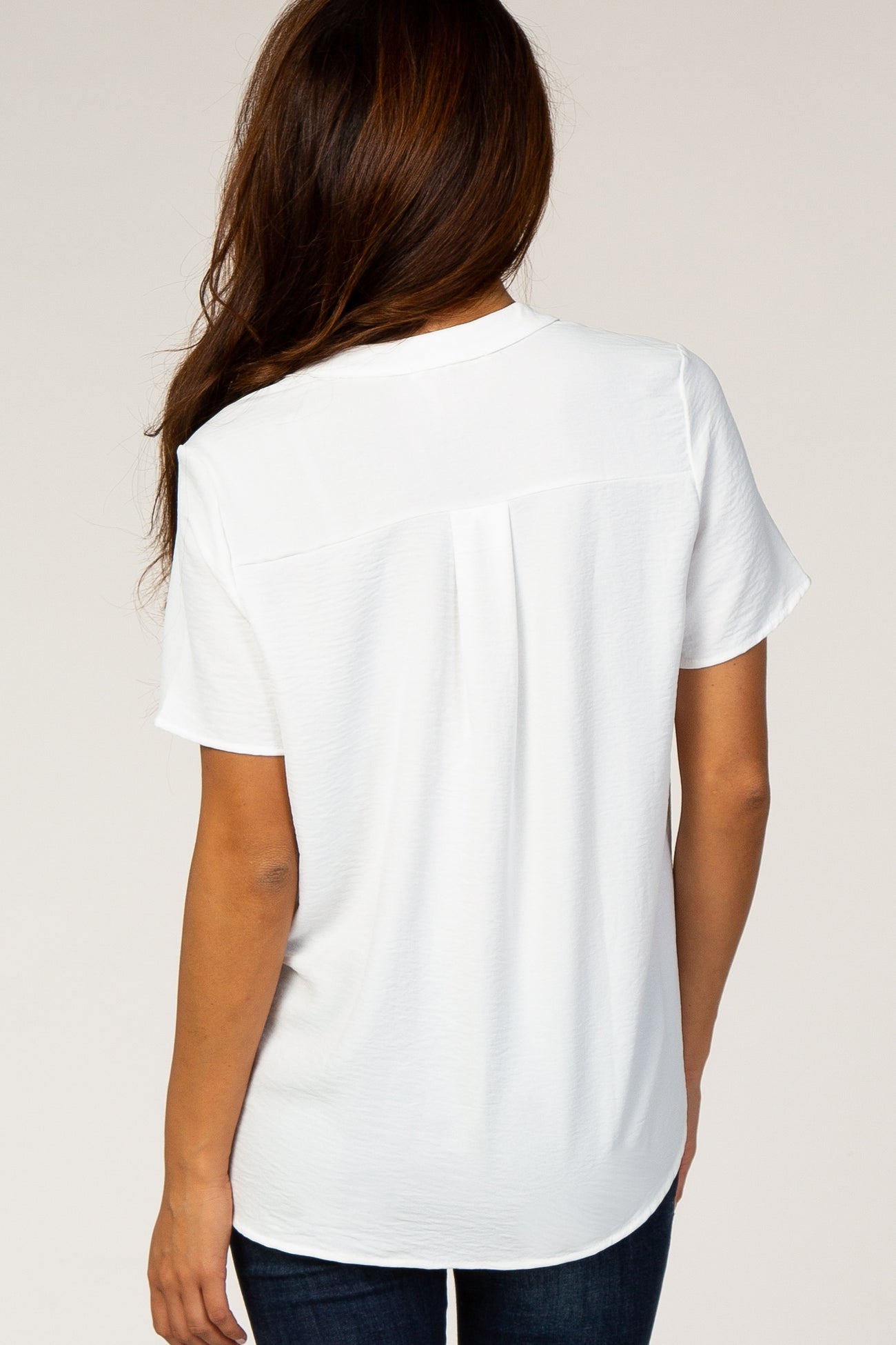 woman wearing a white short sleeve shirt, showing the back view with a relaxed fit and scoop hemline