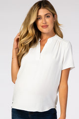 woman wearing a white short sleeve maternity top with a split neckline and visible baby bump