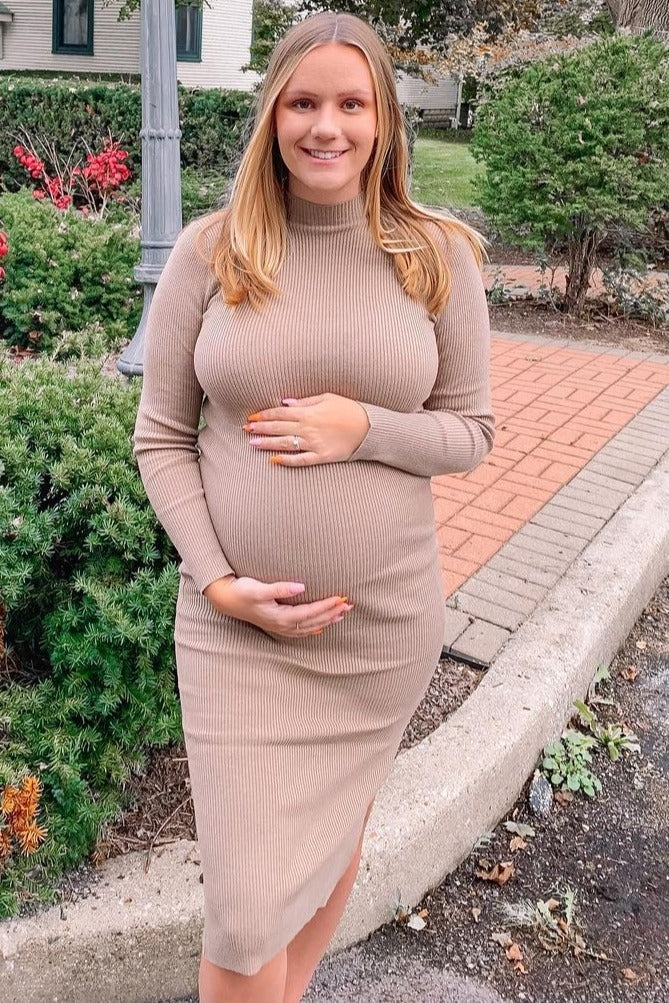 woman wearing a beige ribbed maternity dress and holding her baby bump
