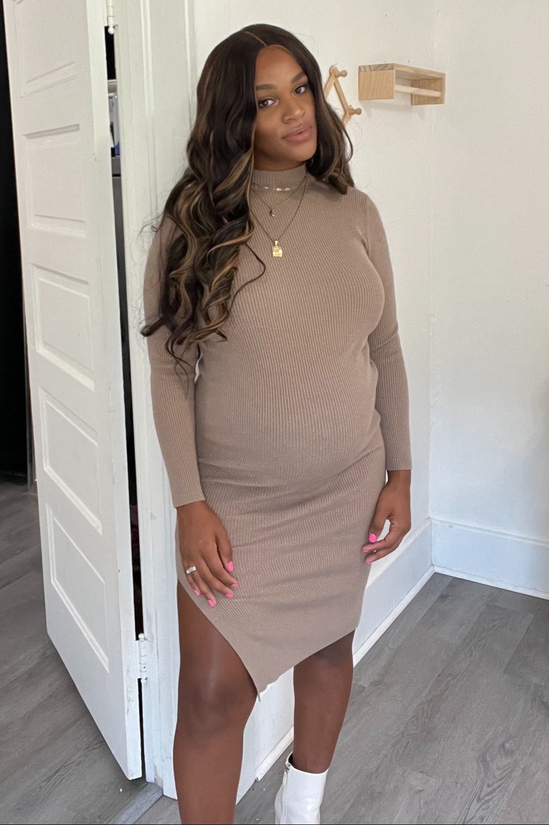 woman wearing a beige ribbed maternity dress with a side slit showcasing her baby bump
