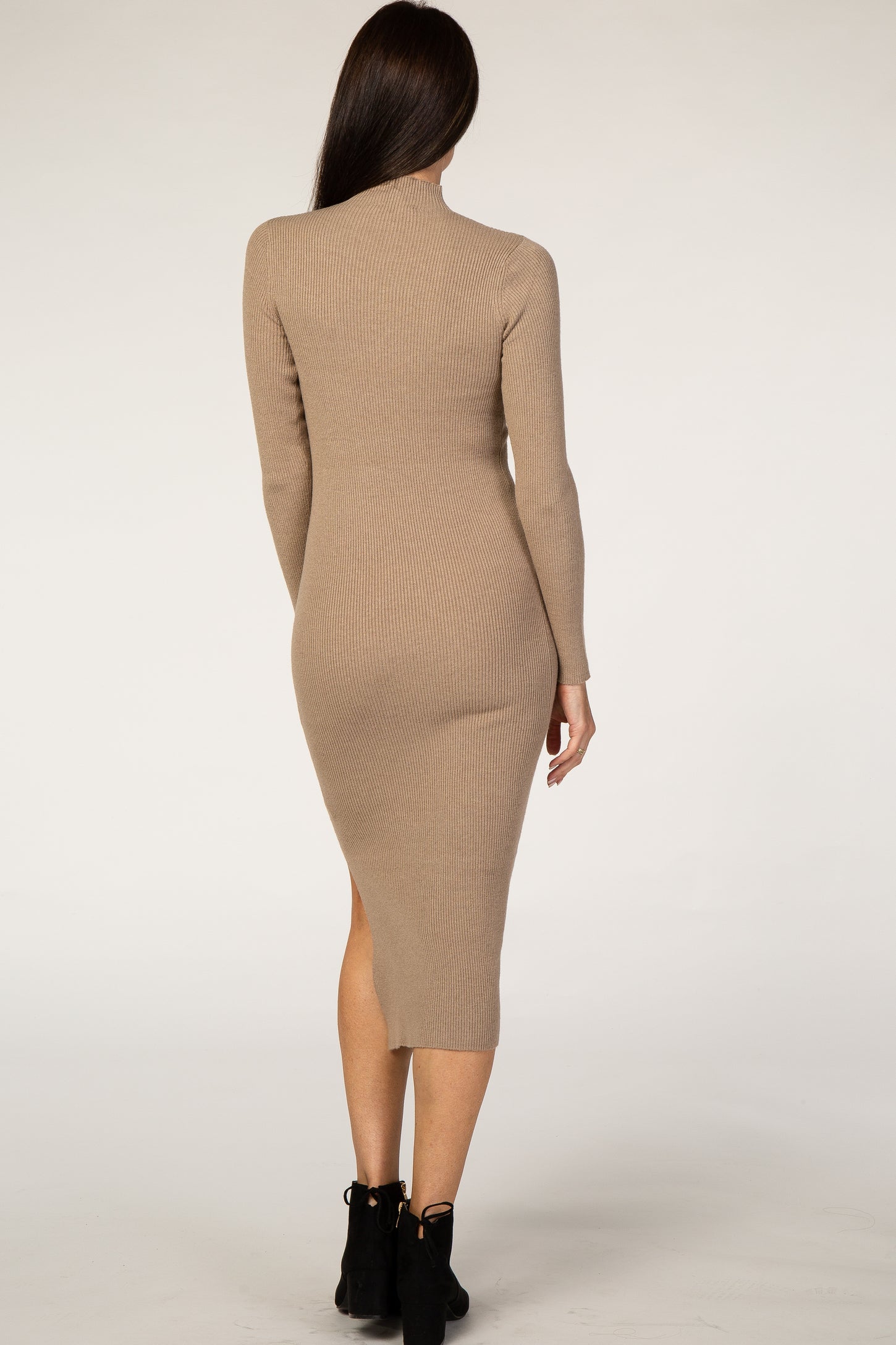 woman wearing a beige ribbed long sleeve midi dress with a side slit, shown from the back