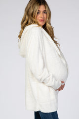 woman wearing a cream fuzzy maternity hoodie and holding her baby bump