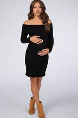 woman wearing a black off-the-shoulder maternity dress and holding her baby bump