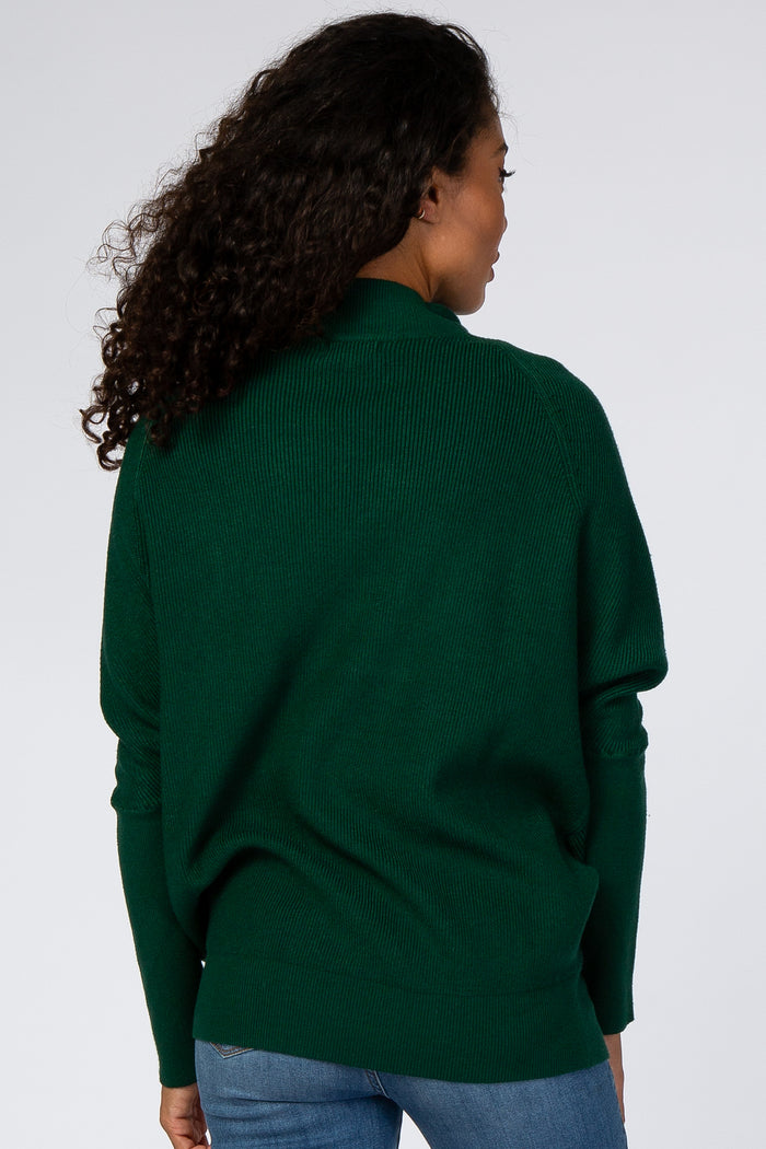 woman wearing a dark green oversized sweater with ribbed texture and long sleeves, shown from the back