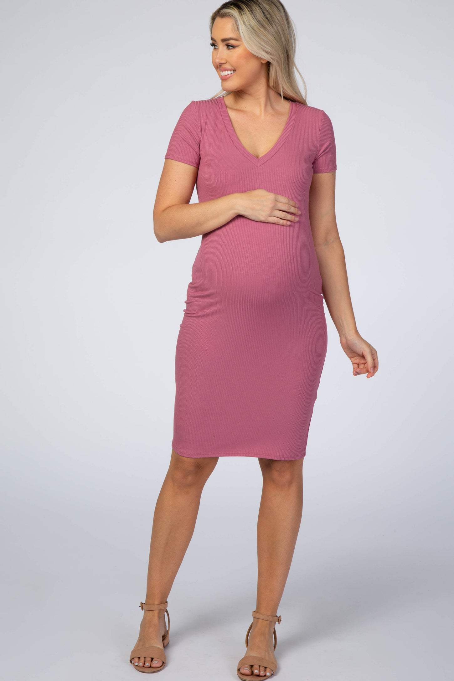 Pregnant woman wearing a mauve ribbed short sleeve maternity dress and tan heels