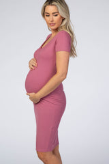 woman wearing a mauve short sleeve maternity dress and showing her baby bump