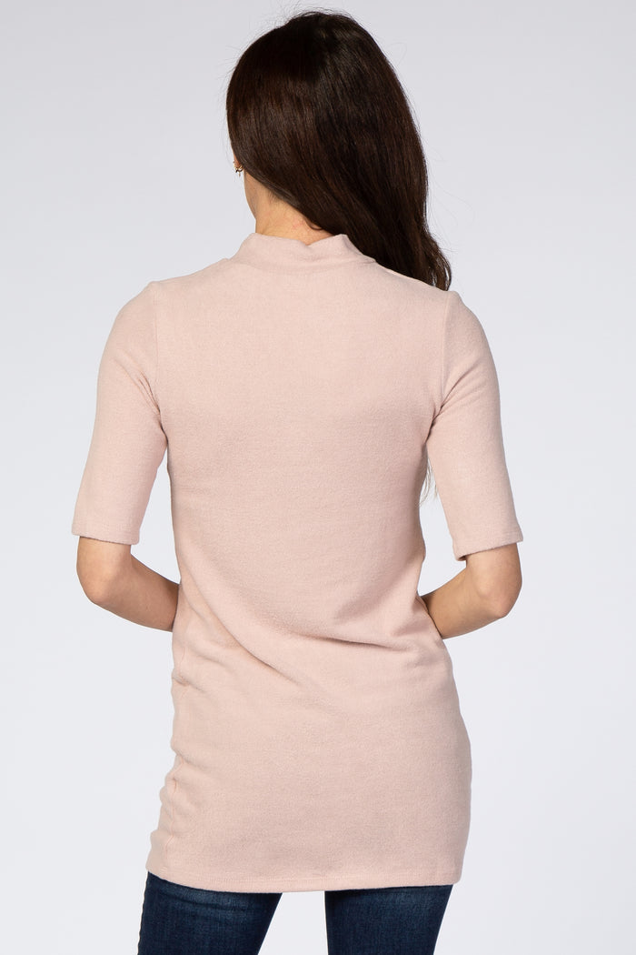 woman wearing a light pink short sleeve tunic sweater, view from the back