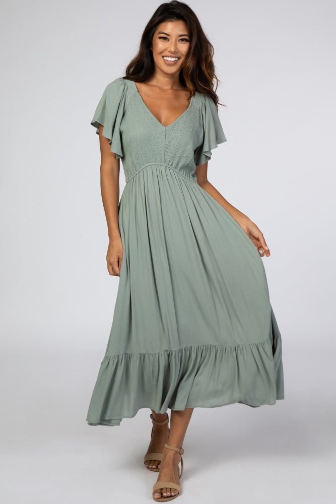 woman wearing a green v-neck midi dress with flutter sleeves and a tiered hem