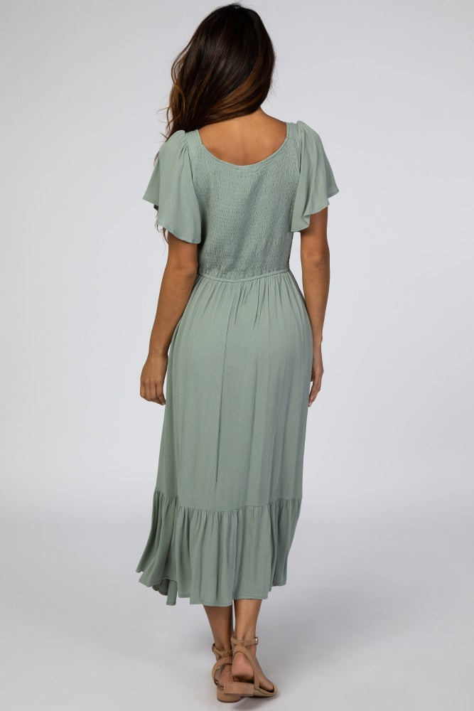 woman wearing a sage green short sleeve maxi dress with a tiered skirt and smocked bodice, shown from the back