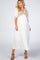 woman wearing a white maternity maxi dress with embroidered floral details and a baby bump visible