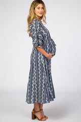 woman wearing a navy and white patterned maternity dress with a tie waist and holding her baby bump
