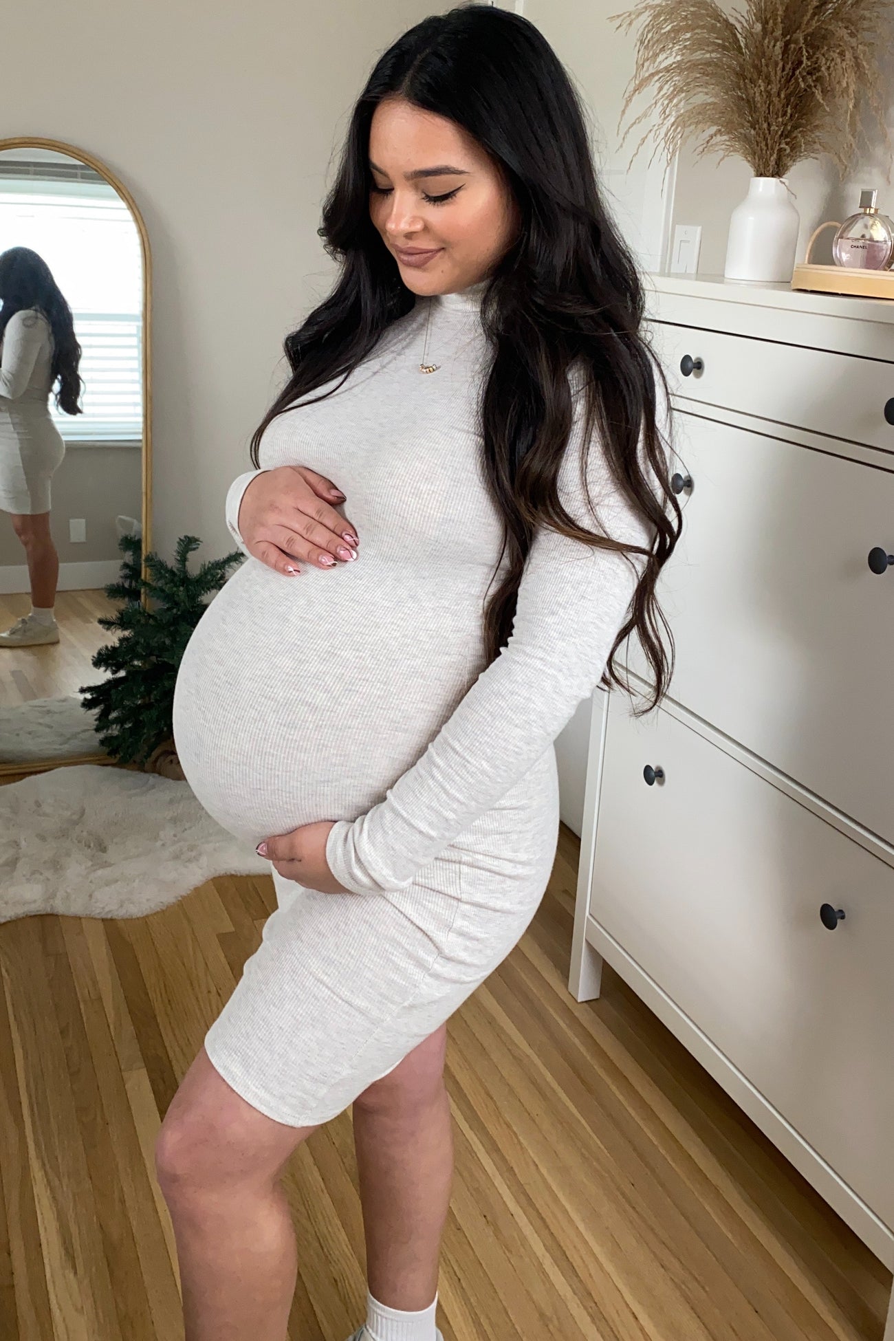 woman wearing a light gray long sleeve maternity dress showing her baby bump