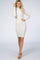 woman wearing a light gray long sleeve fitted dress with a mock neck and a slight swirl detail, standing and smiling