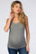 woman wearing a gray ribbed maternity tank top and showing her baby bump while posing thoughtfully