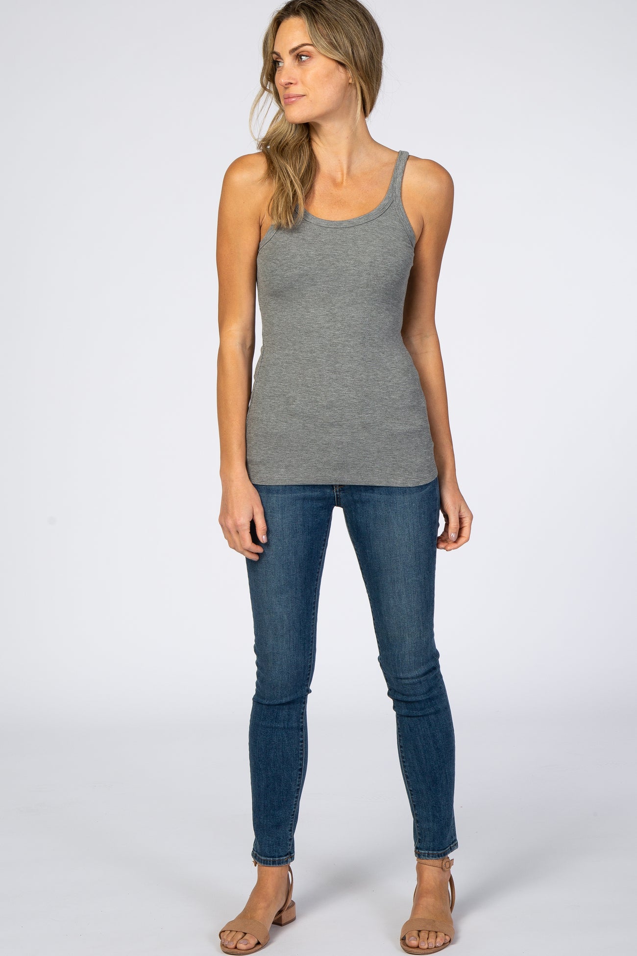 woman wearing a gray ribbed tank top paired with blue skinny jeans and sandals