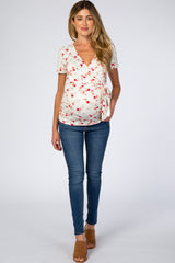 woman wearing a floral print maternity wrap top with a baby bump, paired with skinny jeans and sandals