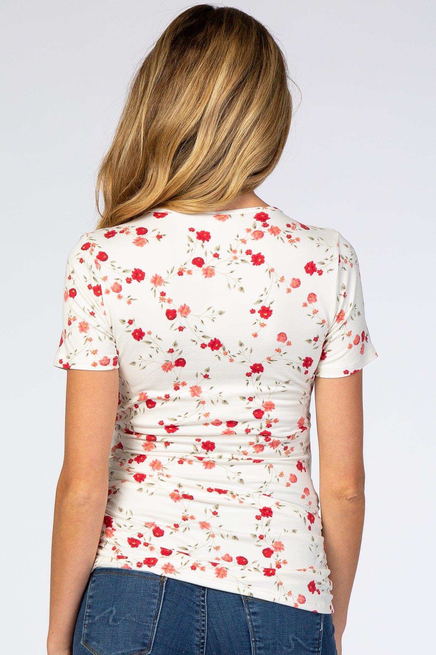 woman wearing a floral maternity top with a fitted style and short sleeves, shown from the back