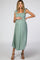 pregnant woman in a sage green smocked maternity midi dress with tie straps and brown heels