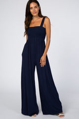 woman wearing a navy blue smocked jumpsuit with wide legs and shoulder straps