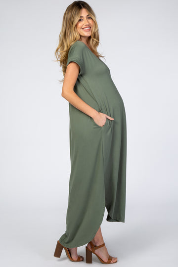 Smiling pregnant woman wearing an olive green short sleeve maternity maxi dress with pockets and brown heels
