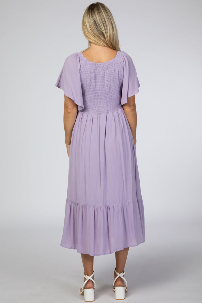 woman wearing a lavender maternity dress with flutter sleeves and a tiered skirt, showing her back