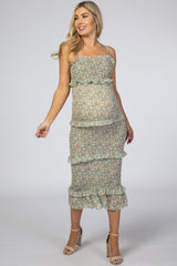 pregnant woman wearing a sage green floral smocked maternity midi dress with ruffles and tan heels