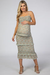 woman wearing a floral print tiered maternity dress with a fitted bodice and holding her baby bump