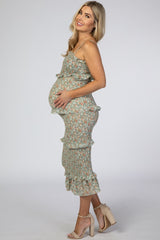 woman wearing a floral print maternity dress with ruffle details and holding her baby bump
