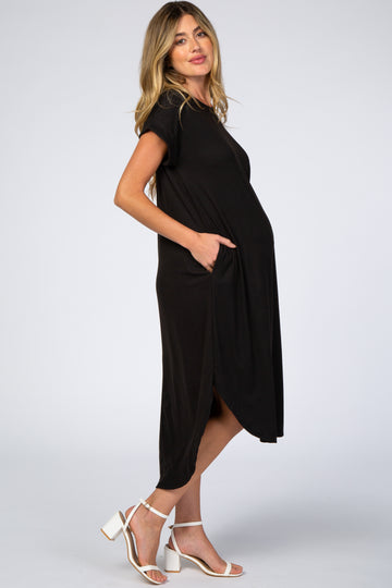 woman wearing a black maternity dress with short sleeves and pockets, showcasing her baby bump