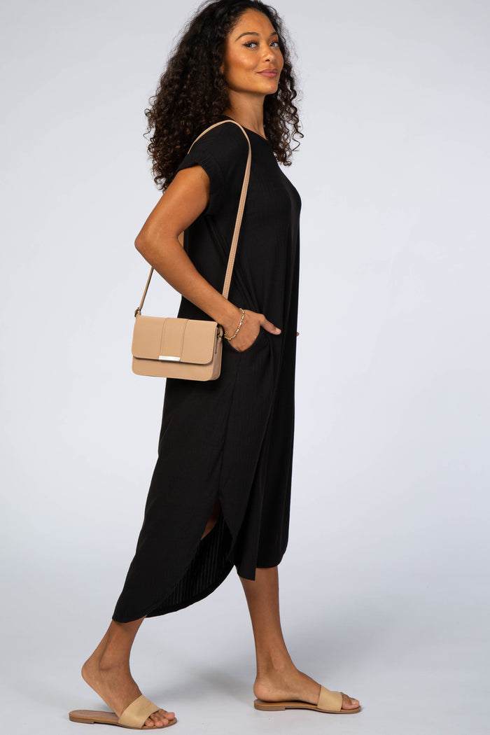 woman wearing a black short sleeve midi dress with side slits and pockets, accessorized with a beige crossbody bag and sandals
