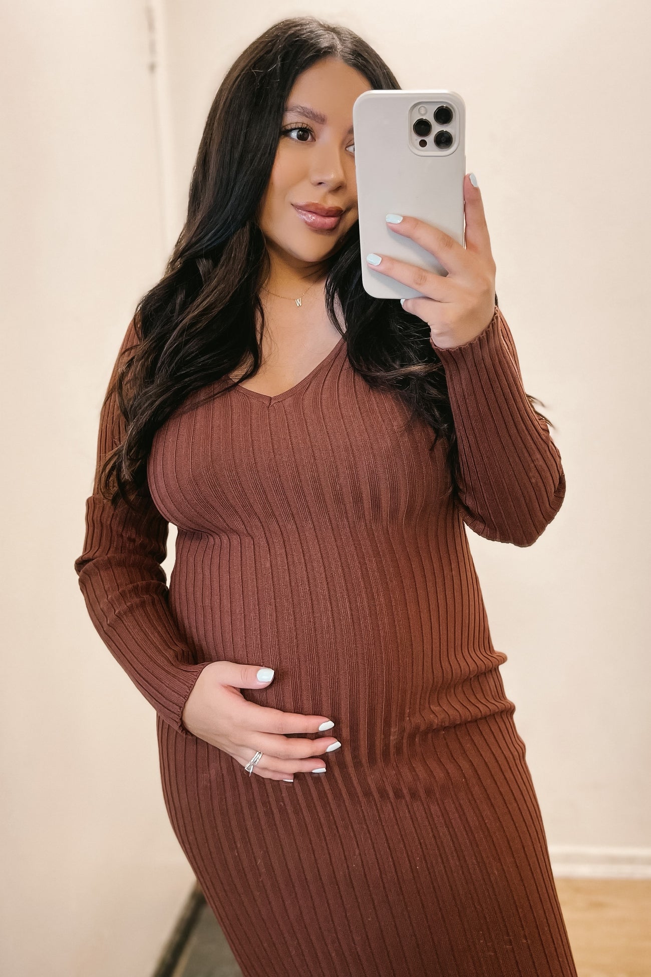 woman wearing a rust ribbed maternity dress with a v-neck and holding her baby bump