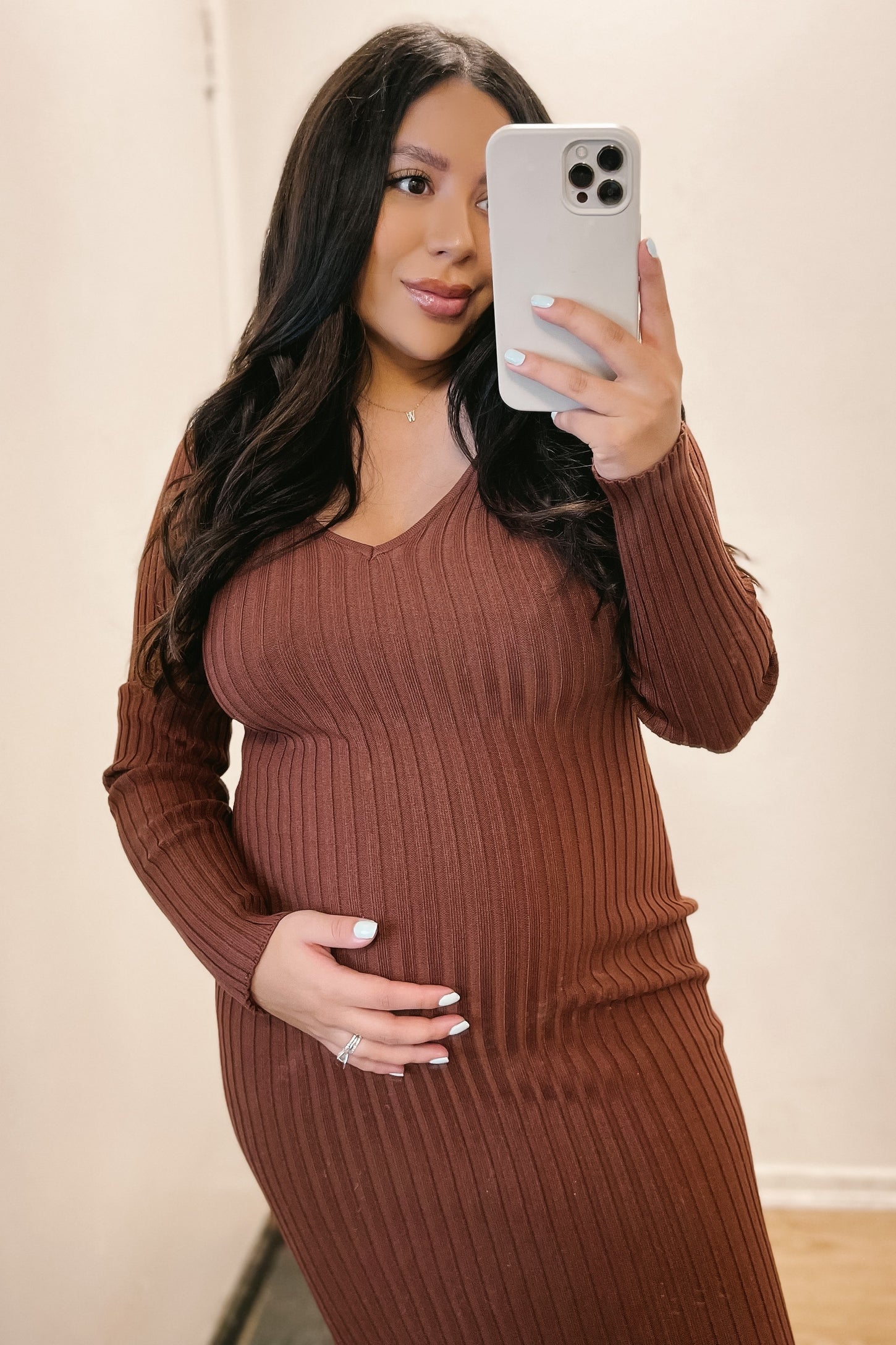woman wearing a rust ribbed maternity dress with a v-neck and holding her baby bump