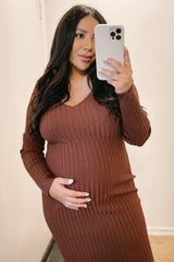 woman wearing a rust ribbed maternity dress with a v-neck and holding her baby bump