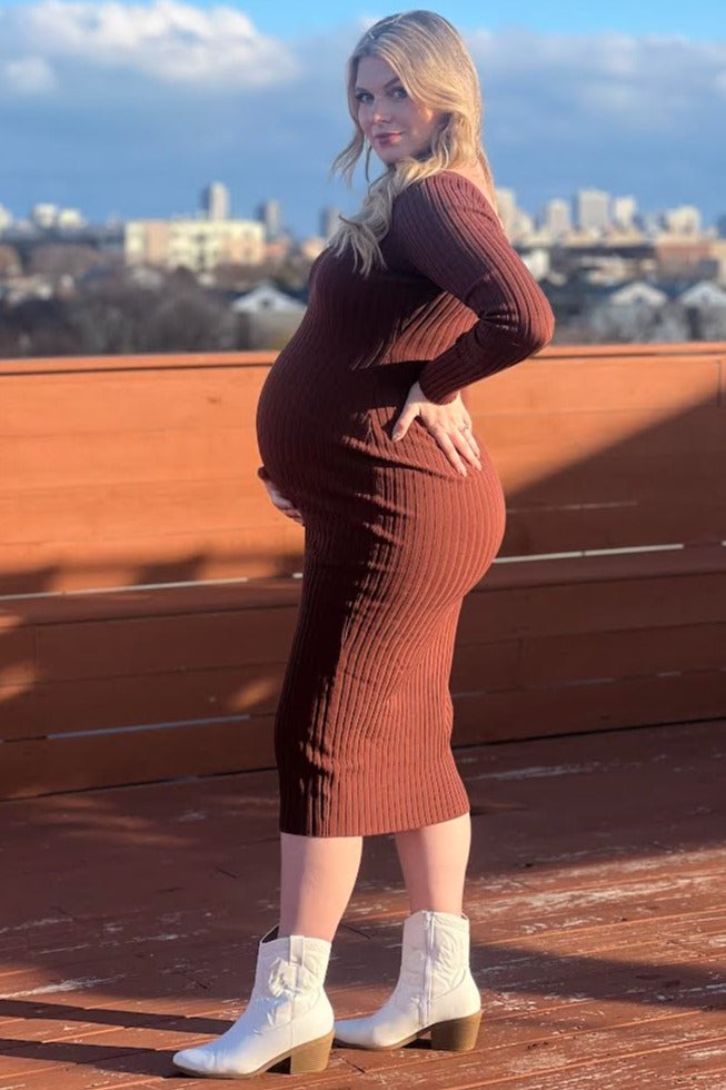 woman wearing a rust ribbed maternity dress showcasing her baby bump and styled with white ankle boots