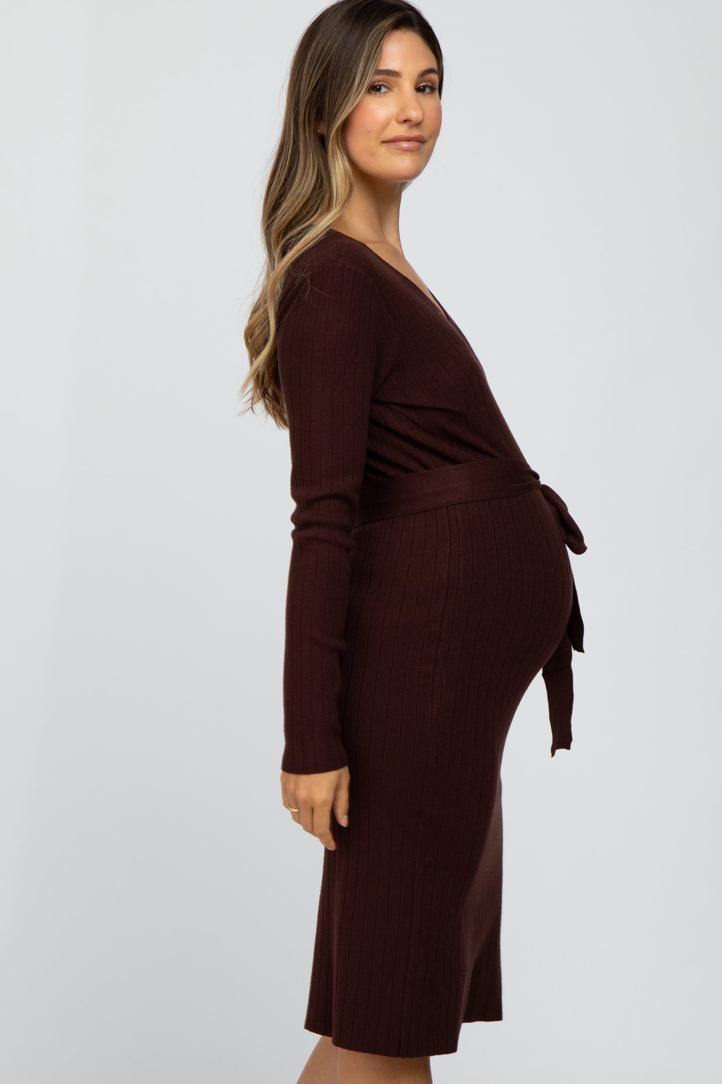 woman wearing a burgundy ribbed maternity dress with a wrap design and tied waist, showcasing her baby bump